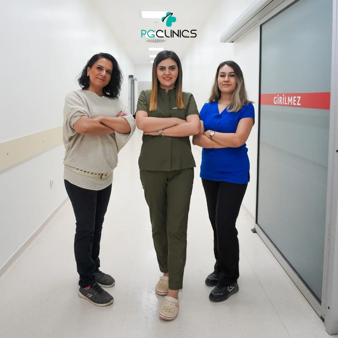 Three people standing together in a bright clinic corridor, with the PG Clinics logo above